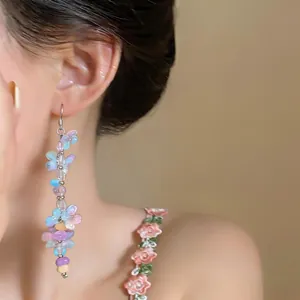 Detailed view of handmade colorful resin flower beaded tassel earrings on model's ear