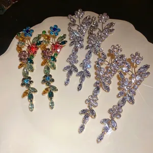 Luxurious sparkling flower tassel earrings with colorful crystals on ceramic plate.