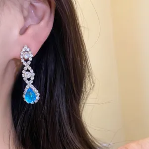 Gros plan sur d'élégantes boucles d'oreilles argentées avec un zircon bleu en goutte