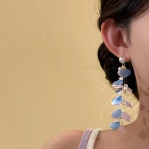 Detailed close-up of long tassel earrings with blue and pink shell petals and pearls