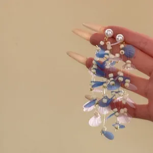 Exaggerated vacation style long tassel earrings with blue and pink petal charms and white pearls.