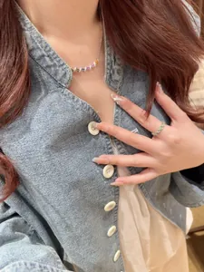 Détail rapproché du collier en zircone colorée et de la bague assortie sur modèle