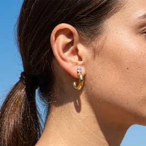 Detailed macro view of elegant gold C-shaped stainless steel stud earring with teardrop zircon