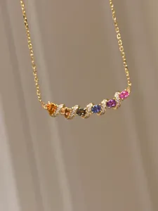 Gros plan d'un collier doré avec des pierres de zircon multicolores et des détails en micro-pavé.