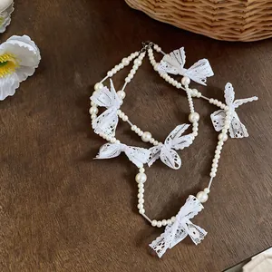 Detailed view of a French sweet style pearl necklace with white lace bow accents