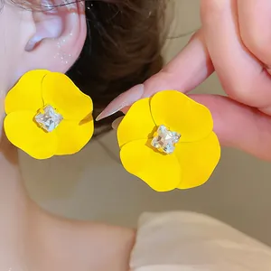Detailed close-up showing vibrant yellow flower earrings with a square clear rhinestone