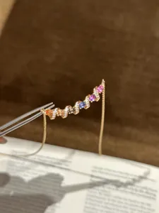 Gros plan d'un collier en zircone colorée avec un motif de ruban torsadé et finition or rose
