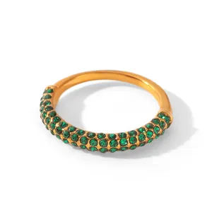 Vue macro d'une bague en acier doré ornée de brillants strass verts pavés avec soin.