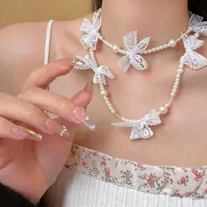 Detailed shot of French style faux pearl necklace featuring delicate white lace bows