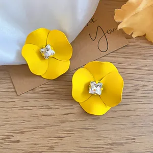 Detail view of yellow flower stud earrings with a central sparkling crystal.
