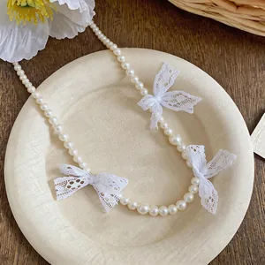 Close-up of French style pearl necklace featuring delicate white lace bows on a plate.