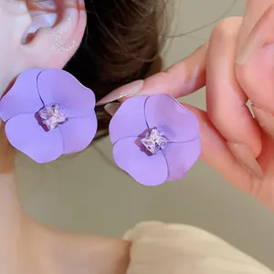 Detailed close-up of purple flower earrings with sparkling crystal center in vacation style.