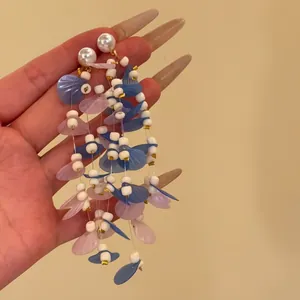 Close-up of bohemian resort style tassel pearl earrings with blue and pink petal beads