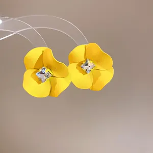 Detailed macro shot of yellow flower earrings with sparkling square crystal centers