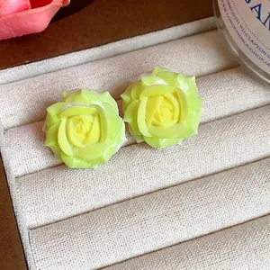 Elegant yellow-green resin rose flower stud earrings presented on a cream jewelry tray