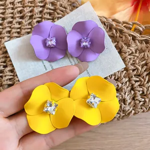 Close-up of yellow and purple matte flower earrings with square crystals