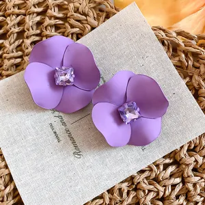 Close-up detail of purple matte flower earrings with sparkling square crystal centers