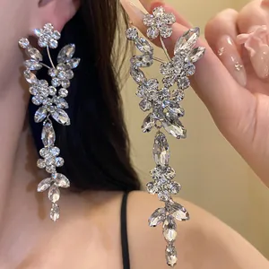Detail view of luxury flower tassel earrings with sparkling rhinestones on model ear.