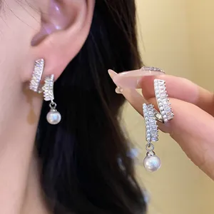 Close-up of elegant silver needle earrings with CZ stones and white pearl drops