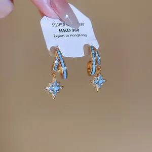 Detailed macro view of gold-plated double layer hoop earrings with blue star charms