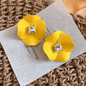 Close-up of vibrant yellow flower stud earrings with center square rhinestone detail.