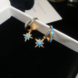 Detail of gold-tone star earrings with blue turquoise inlay in a black gift box.