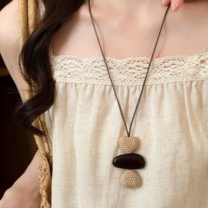 Handmade bohemian long necklace featuring woven hearts and a dark smooth stone pendant