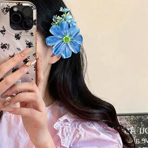 Pince à cheveux fleur en tissu bleu sur modèle aux longs cheveux noirs élégants
