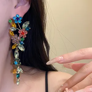 Close-up view of elegant colorful crystal flower tassel earrings worn on a person's ear.
