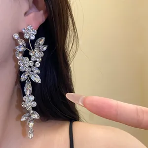 Close-up of sparkling rhinestone flower tassel earrings worn on ear