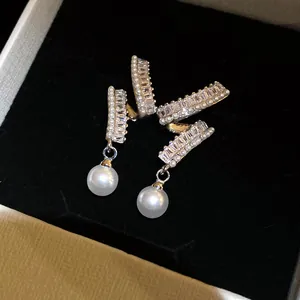 Detail view of elegant silver earrings with shimmering zirconia and round pearls.