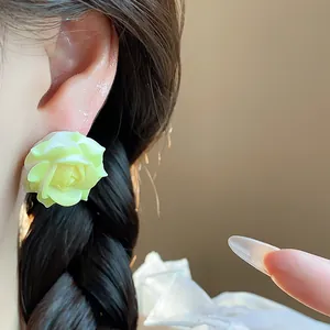 Detailed close-up view of a model wearing a sweet light green resin rose earring