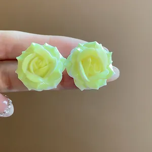 Detail macro shot of pale yellow resin rose flower stud earrings with silver needles.