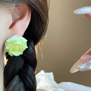 Close-up detail of sweet resin yellow rose flower stud earrings worn on earlobe