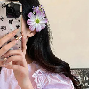 Détail d'une pince à cheveux fleur en tissu violet sur d'élégants cheveux sombres ondulés