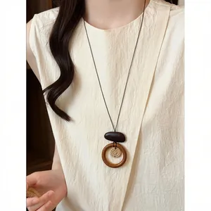Detail of a bohemian woven flower pendant necklace worn with a cream textured top.