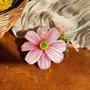 Détail d'une pince à cheveux fleur rose en tissu avec une texture délicate.