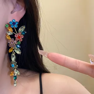 Close-up of colorful floral rhinestone tassel earrings with shimmering crystals on model's ear.