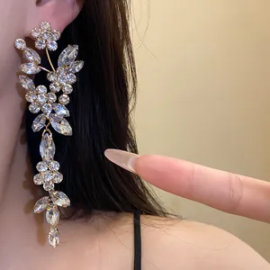 Detailed close-up of sparkling rhinestone flower tassel earrings worn on ear