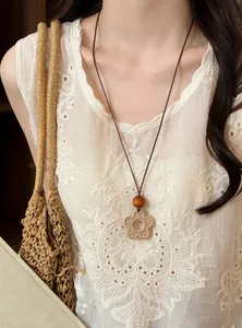 Close-up of bohemian woven flower necklace with wood bead detail on white lace top