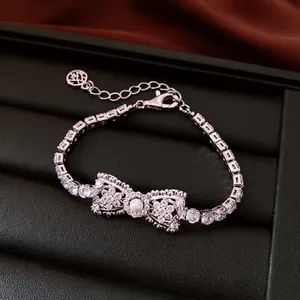 Elegant silver-toned bow bracelet with cubic zirconia and central pearl accent decoration
