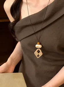 Detailed close-up showing a bohemian woven square pendant necklace worn by a model.