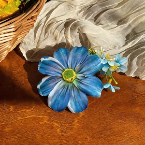 Gros plan d'une pince à cheveux fleur en tissu bleu avec des détails délicats de pétales.