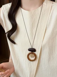 Close-up detail of a bohemian woven floral necklace with a wooden ring and dark stone pendant