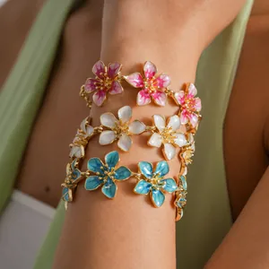 Close-up of enamel flower bracelets in pink, white, and blue on a wrist