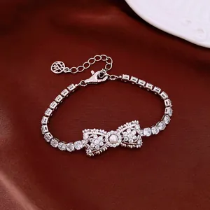 Close-up of elegant bow-shaped bracelet with pearls and shimmering zircons on dark fabric