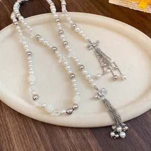 Elegant long pearl beaded necklace with rhinestone bow tassels on cream tray