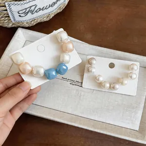 Close-up of geometric pearl stud earrings on white display cards