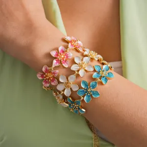 Close-up detail of colorful enamel flower bracelets in pink, white, and blue