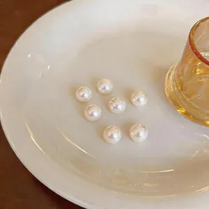 Macro detail showing seven lustrous white round pearls on a minimalist ceramic plate